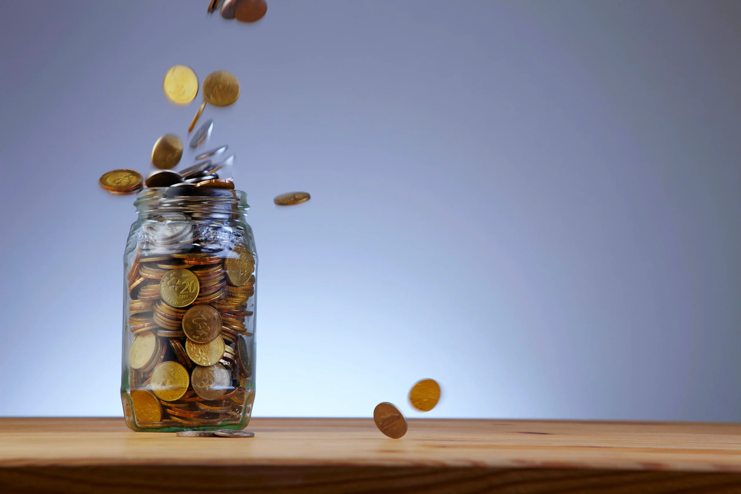 Coins in a glass jar on a wooden table